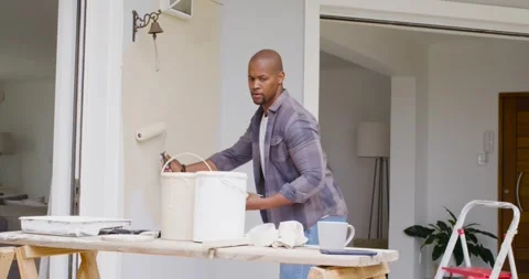 Homeowner is picking up roller, loading paint, painting entry wall to refresh 動画素材 335514708
