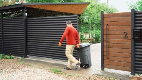 The homeowner remotely opens the gate to roll out the dumpster. Stock Footage 154907035