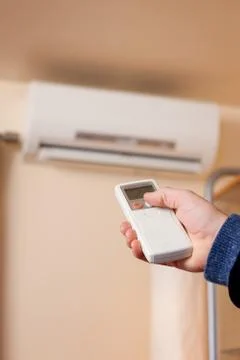 Homeowner using remote to operate ductless heat pump Stock Photos
