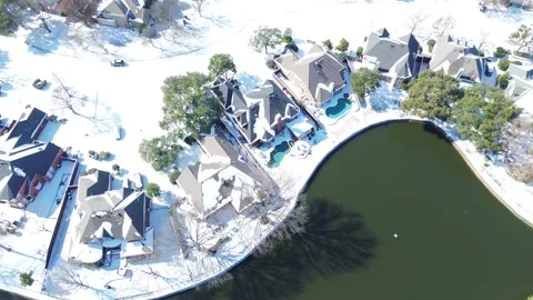 Homes bordering the pond at Waterside Estates show Winter Storm Fern snowfall Stock Footage 327705174