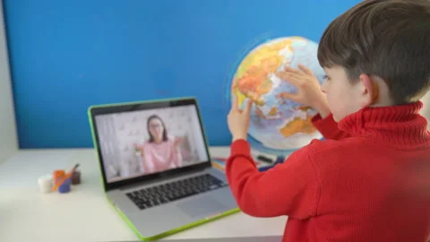 Homeschool kid studying a globe using laptop computer learning geography at home Stock Footage 152901577