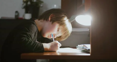 Homeschooling concept. A child doing homework at home under the light of lamp. Stock Footage 147684712