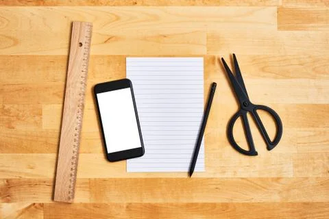 Homework concept. Smartphone, an empty sheet of paper and office or school su Stock Photos