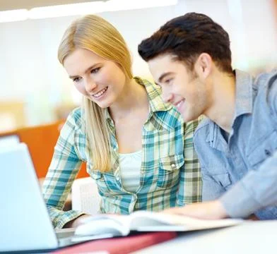 Homework in the modern age. Two smiling students helping each other with their Stock Photos