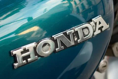 Honda motorcycle emblem mounted on metallic blue vehicle fuel tank Stock Photos