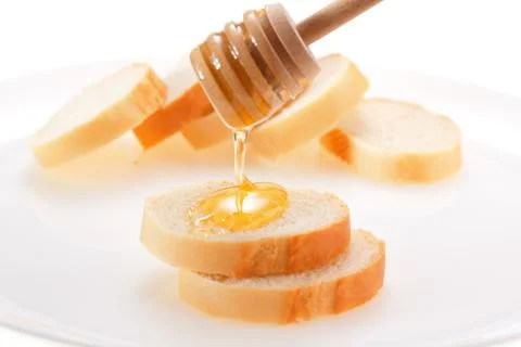 Honey is applied to the surface of bread. Isolated on a white background. Stock Photos