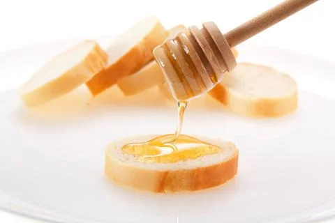 Honey is applied to the surface of bread. Isolated on a white background. Stock Photos