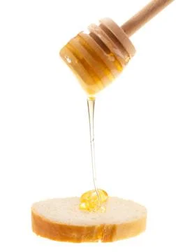 Honey is applied to the surface of bread. Isolated on a white background. Stock Photos