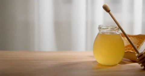 Honey background. Sweet honey in a glass jar and a honey spoon on a wooden ta Stock Footage 207724853