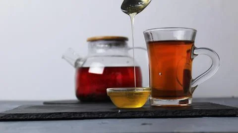 Honey drains from the spoon in a thin stream. Honey and tea treatment folk re Stock Photos