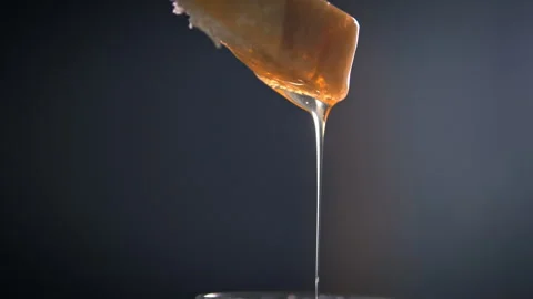 Honey dripping from a slice of bread into a honey jar Stock Footage 274707353