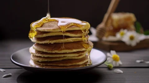 Honey dripping on the stack of pancakes for breakfast on the wooden table Video stock 105143757