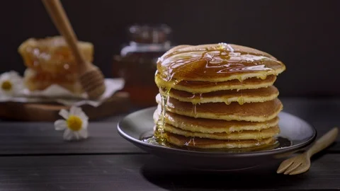 Honey dripping on the stack of pancakes for breakfast on the wooden table Stock Footage 106494385