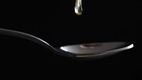 Honey dripping from the stainless tea spoon on black background Stock Footage 83036705