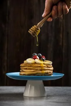 Honey drop over pancakes stack with fresh fruits Stock Photos