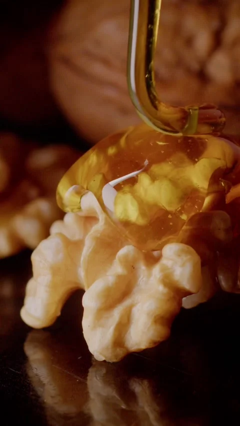 Honey flows appetizingly over a walnut 스톡 동영상 237705386