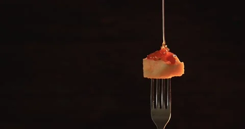 Honey flows on a piece of cheese. Cheese on a fork. Black background Stock Footage 244840800