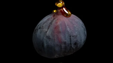 Honey flows in a thin stream onto the rotating fig on a black background. Stock Footage 253567170
