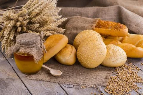 Honey in a jar, slice of bread, wheat and milk on an old vintage planked wo.. Foto stock