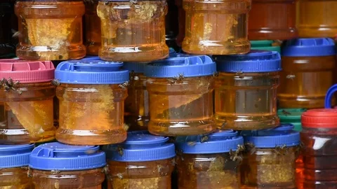 Honey in plastic jars with flying bees Stock Footage 97813031