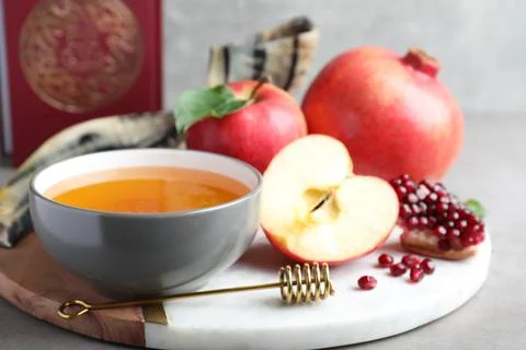 Honey, pomegranate, apples, shofar and Torah on grey table. Rosh Hashana holi Stock Photos