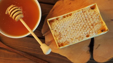 Honey pot and dipper at rustic table with bread, raisins and Honey comb, top Video stock 91193198