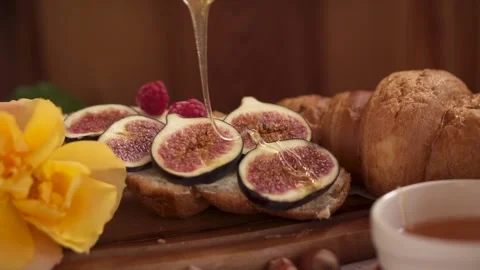 Honey is poured onto croissant. fresh pastries and figs. Coffee nuts. Cozy snack Stock Footage