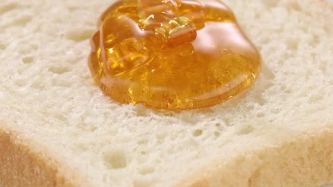 Honey is poured on a piece of bread. close-up. viscous stream of honey. Stock Footage 242104830
