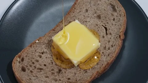 Honey Pouring Over Bread and Butter – Breakfast Close Up Stockbeeldmateriaal 335976460