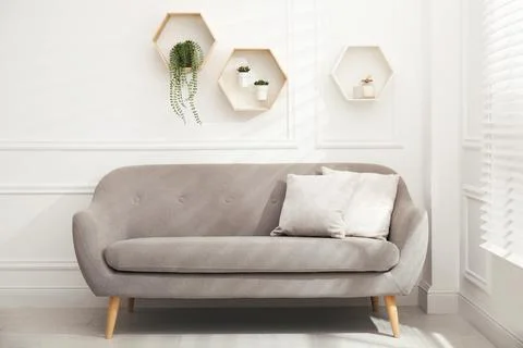 Honeycomb shaped shelves with decorative elements and houseplants on white wa Stock Photos