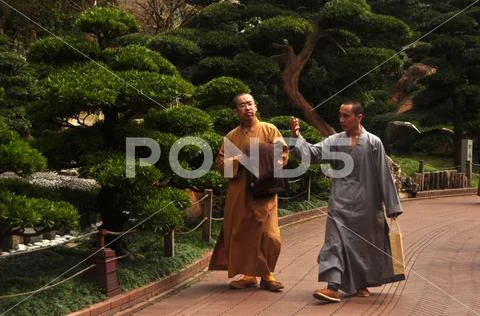 HONG KONG - 22th FEBRUARY, 2015: Monks walking in green oriental garden, View Stock Photos