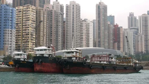 HONG KONG, freighters side by side docked at wharf with tower blocks skyline Vidéo 73645902
