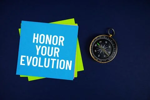 Honor Your Evolution text written on sticky note with compass on blue  back.. Stock Photos