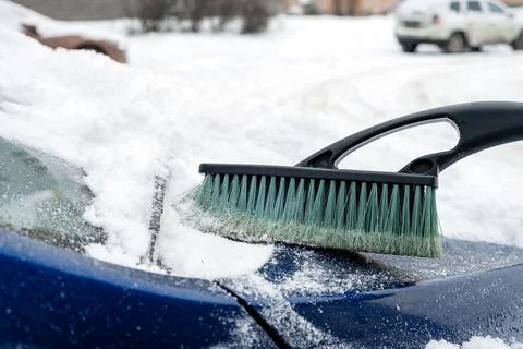 The hood of a car is cleaned with a brush after a snowfall Stock Photos