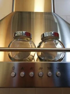 Hood for the kitchen. Silver. Two spice jars. Glass with iron lids Stock Photos