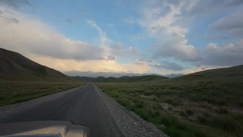 Hood mounted POV on an empty steppe road at golden hour, Kyrgyzstan Stockbeeldmateriaal 347242804