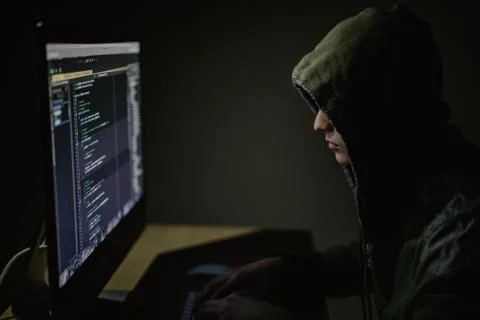Hooded computer hacker stealing information with pc in Dark room background 스톡 사진