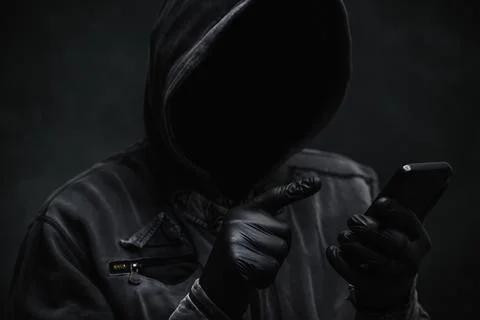 Hooded computer hacker using smartphone Stock Photos