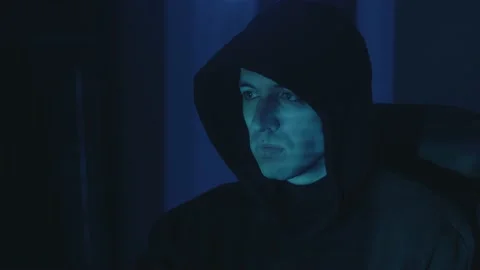 Hooded dangerous hacker programmer working on computer scheming cyber attack on Stock Footage 147249417
