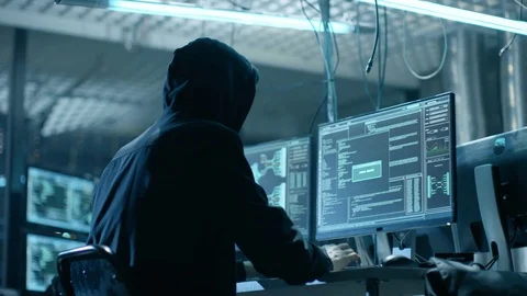 Hooded Hacker Breaks into Corporate Data Servers from His Underground Hideout. Stock Footage