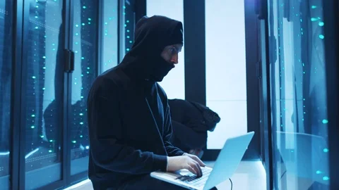 Hooded hacker coding phishing attacks on laptop breaking into secure server Stock Footage 120695632