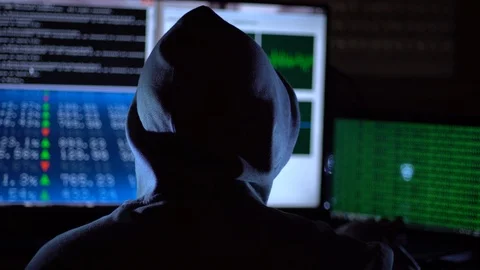 Hooded hacker coding security data on a computer in dark room Stock Footage 89621084