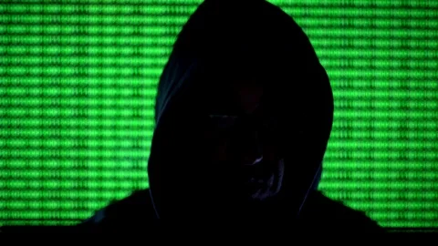 Hooded hacker coding security data on a computer in dark room Stock Footage 89626650