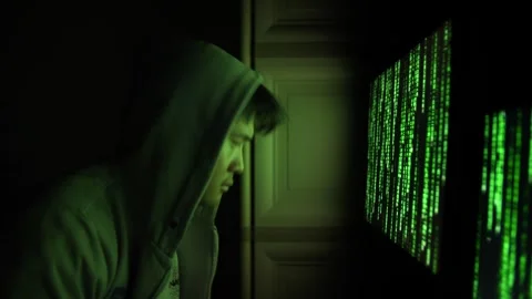 Hooded Hacker Examining Green Code on Computer Screens in Dark Room Stock Footage 336049496