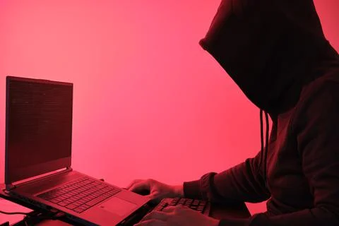 Hooded hacker in front of a computer for organizing data breach attack 스톡 사진
