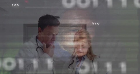 Hooded hacker glancing causing binary glitch while medical doctors reviewing and Stock Footage 312082116