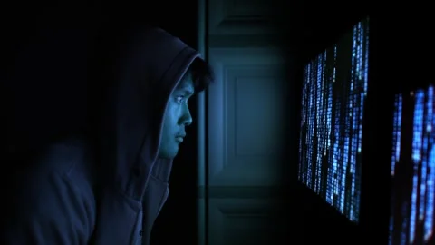 Hooded Hacker Illuminated by Blue Computer Code Screen Stock Footage 336475077