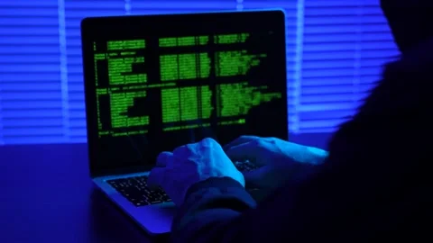 Hooded hacker using laptop computer, close-up. Anonymous hacker sitting in .. Video stock 288979452