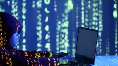 Hooded hacker using laptop with green digital code reflections in a Stock Footage 307020266