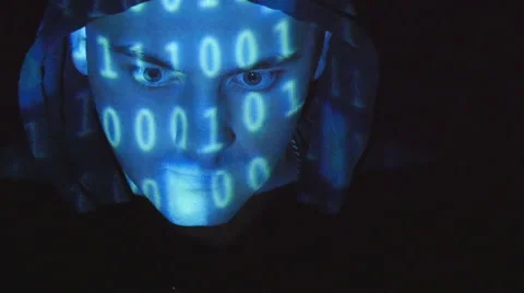Hooded hacker working on a computer, binary code projecting on his face. Video stock 64817649